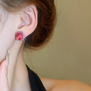 Close-up of elegant pink rhinestone earrings worn by a model with a soft blurred background