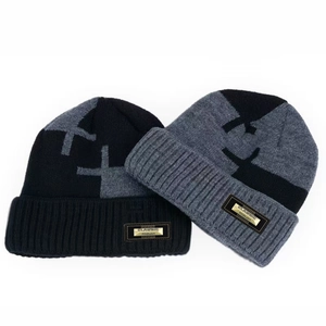Detail of ribbed knit beanies with classic metal tag and cross pattern for winter