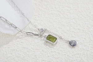 Macro shot of S925 silver necklace with rectangle green gemstone and paperclip link detail