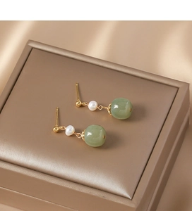 Detailed view of vintage gold earrings with freshwater pearls and green jade beads