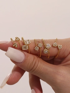Gros plan de bagues dorées superposées aux motifs de cœur et géométriques avec zircons
