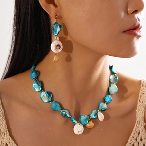 Detail view of seaside shell necklace with blue polished shell slices and conch pendants
