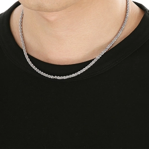 Gros plan d'un collier chaîne torsadée en acier inoxydable argenté sur un modèle homme