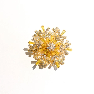 Detailed close-up of a rotating snowflake brooch with gold plating and sparkling zircons