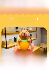 Detail shot of a cute Capybara keychain holding an orange with PVC and alloy materials