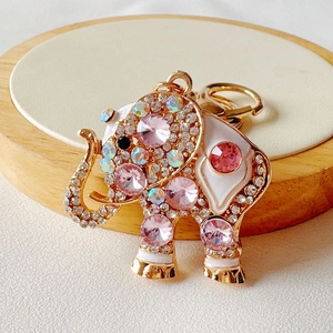 Detail of a gold elephant keychain with white enamel and sparkling pink rhinestones