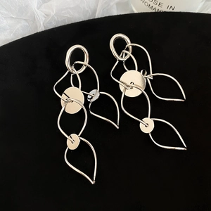 Macro shot of silver geometric hollow tassel earrings on black velvet display