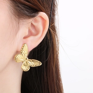 Detailed close-up of a vintage golden butterfly stud earring worn on a model's ear