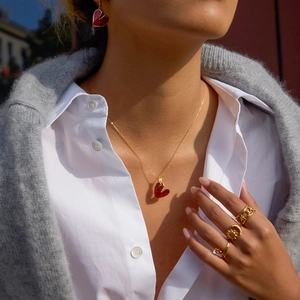 Dettaglio della collana a cuore in acciaio 18K e anelli celesti su una modella