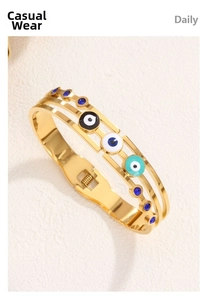 Detail of gold evil eye cuff bracelet with triple enamel eyes and blue rhinestone accents