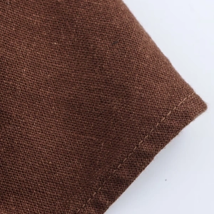 Detailed macro view of high-quality brown linen blend fabric and stitching for dresses
