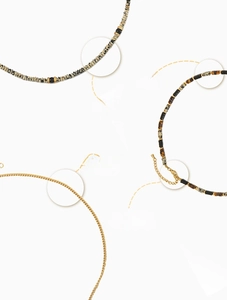 Detailed macro view of natural speckled stone beads and polished gold plated chain links