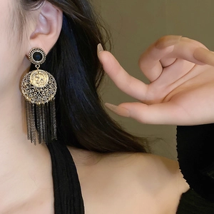 Détail macro de boucles d'oreilles vintage dorées avec pierre noire et longues franges