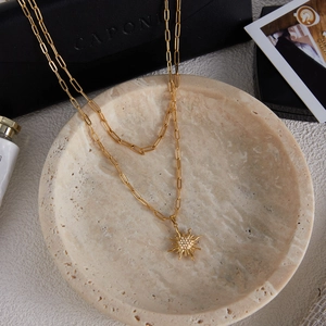 Collana a doppio strato in oro 18K con catena a graffetta e ciondolo a sole con strass