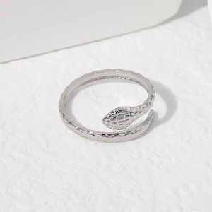 Détail d'une bague serpent argentée avec des textures d'écailles et un design ouvert réglable