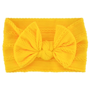 Close-up of yellow soft knitted baby headband with a large bow and ribbed texture