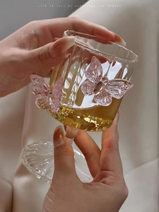 Detail of ribbed glass champagne flute featuring 3D pink butterfly accents and yellow drink