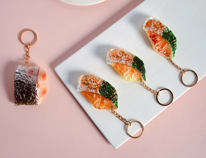 Porte-clés de filet de poisson réaliste avec chaîne dorée et feuille sur assiette
