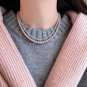 Close-up of double-layer pale pink pearl necklace on elegant autumn knitwear