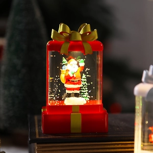 Macro detail of red gift-box shaped LED water lantern with Santa and gold ribbon