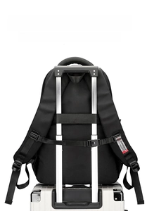 Detail of the black backpack's rear luggage strap mounted on a silver suitcase handle
