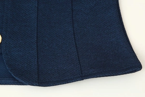 Gros plan du tissu en sergé bleu foncé avec des boutons dorés et des coutures précises