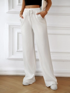 Detail of white high-waisted wide-leg knit trousers with drawstring and ruffle hem