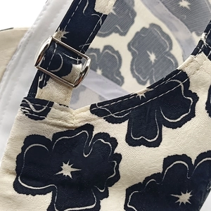 Detailed macro view of cream floral baseball cap with navy print and silver buckle
