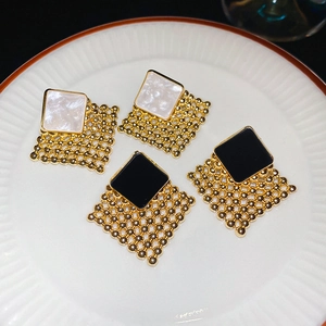 Detail view of woven diamond-shaped stud earrings in black and white enamel finishes