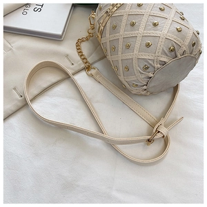Close-up of cream pineapple-shaped bucket bag with gold rivets and chain strap detail