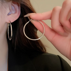 Close-up of minimalist silver hoop earrings showcasing the sleek metal texture and clasp