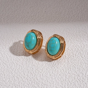Close-up of retro gold-tone earrings with oval turquoise stones and hammered metal texture
