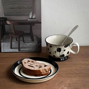 Detail of vintage hand-painted ceramic coffee cup with tulip pattern on wooden desk