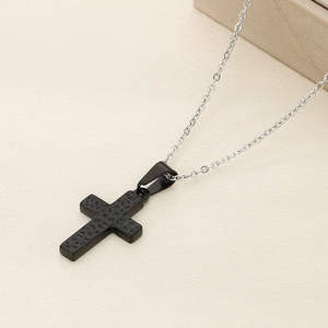 Detailed close-up of a black hammered cross pendant on a silver metal chain necklace
