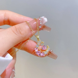 Macro shot of gold moon and heart pendant necklace with pink and white cubic zirconia