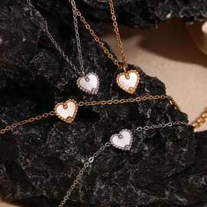 Détail de colliers cœur plaqués or 18 carats avec nacre blanche sur fond de roche