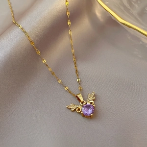 Elegant gold titanium steel necklace with a purple zircon stone on warm silk background