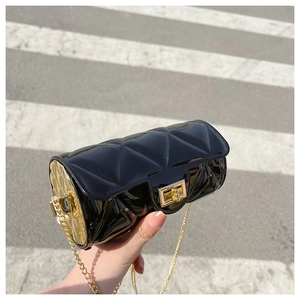 Detail of black patent leather cylinder bag with quilted pattern and gold chain strap