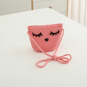 Dettaglio della borsa a tracolla in paglia rosa con viso di gatto e tracolla intrecciata