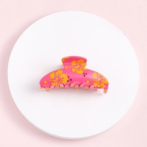 Top view of pink hair claw clip with orange flower patterns on white circular base