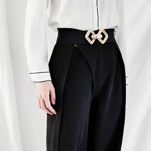 Détail de la boucle géométrique dorée sur une ceinture élastique noire pour femme