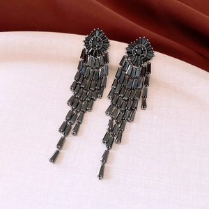 Detailed close-up of 14K gold plated long black fringe tassel earrings on velvet background