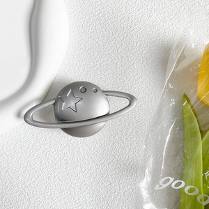 Close-up of silver planet phone grip with engraved stars and rings on white texture