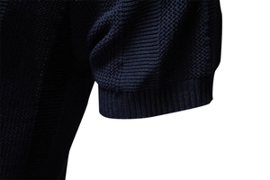 Detailed macro view of dark blue waffle knit texture and ribbed cuff on men's polo shirt