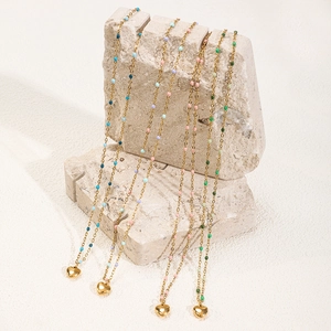 Détail de colliers dorés avec perles colorées et pendentifs en cœur sur des pierres