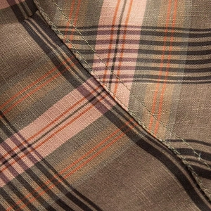 Macro shot of plaid shirt fabric with brown, pink, and orange woven patterns