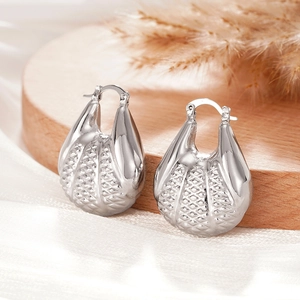 Détail de boucles d'oreilles argentées en coquillage sur bois avec soie et foin