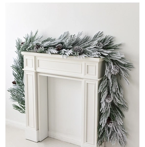 Detailed snowy artificial pine garland with natural pinecones on a white fireplace mantle