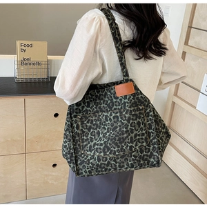 Detail of leopard print canvas tote bag featuring large outer pocket and leather patch