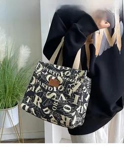 Détail du sac à lunch en tissu Oxford noir avec écusson logo et motif élégant imprimé